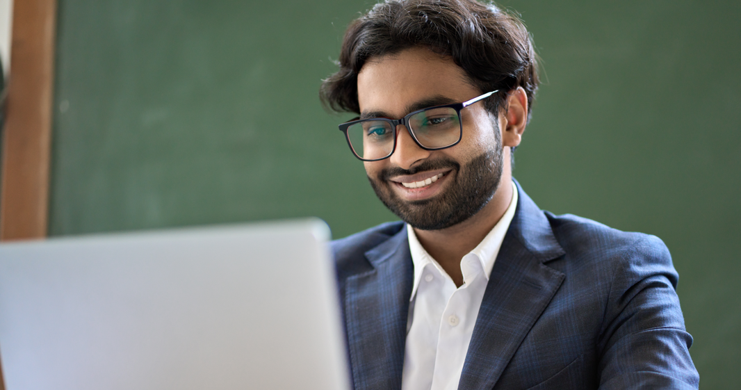 man smiling with glasses looking at laptop